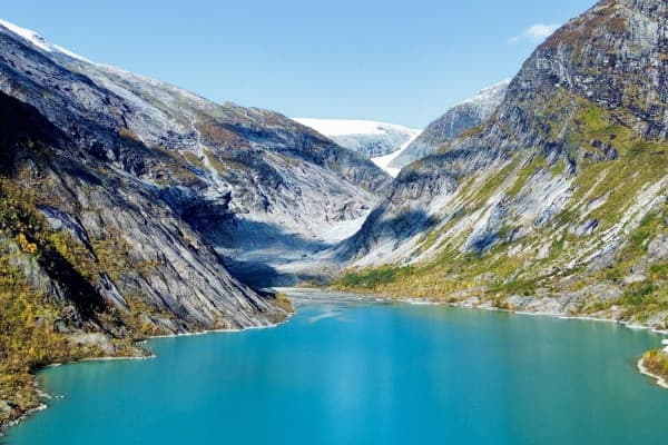 View of the stunning Nigardsbreen Glacier in Norway, with its massive ice tongue descending into a turquoise glacier lake. Surrounded by steep, rocky mountains, this iconic natural wonder highlights the raw beauty and power of Norway's glacial landscapes.