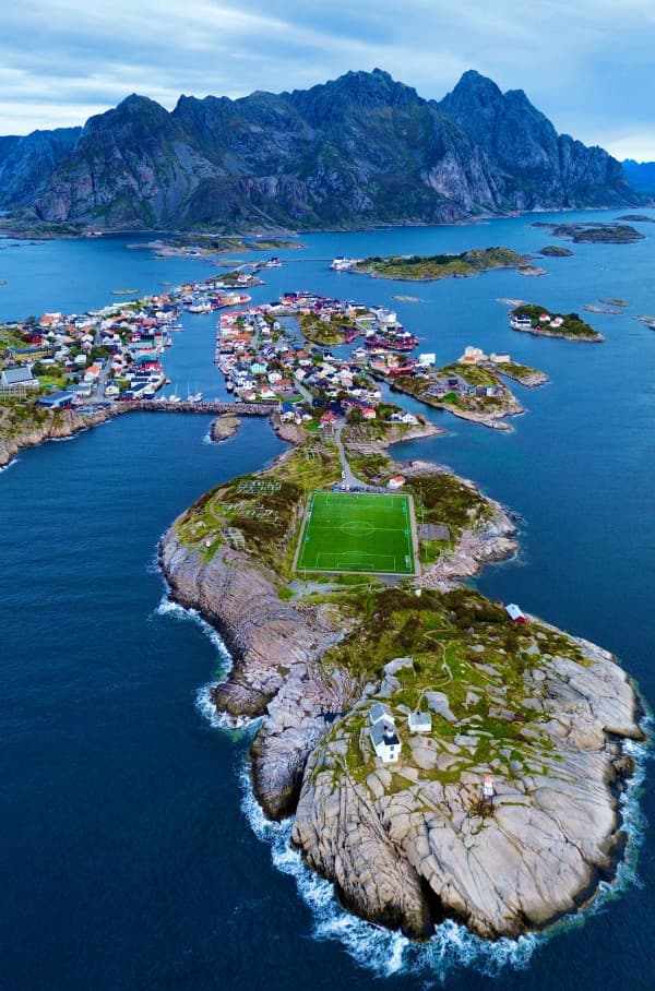 Aerial view of the iconic Henningsvær football field, located on a rocky island in the Lofoten Islands, Norway. Surrounded by dramatic mountains and the North Sea, this unique football pitch is nestled in the scenic fishing village of Henningsvær, highlighting the striking natural beauty and remote charm of the region.